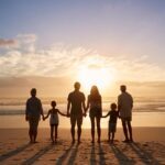 A family standing on the beach holding hands.