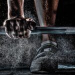 A person is holding onto the bar of a bench press.